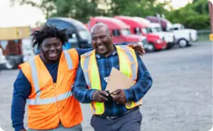 An African American Man and woman smiling at work, wearing safety vests